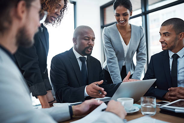 Shot of a group of businesspeople discussing something on a laptop